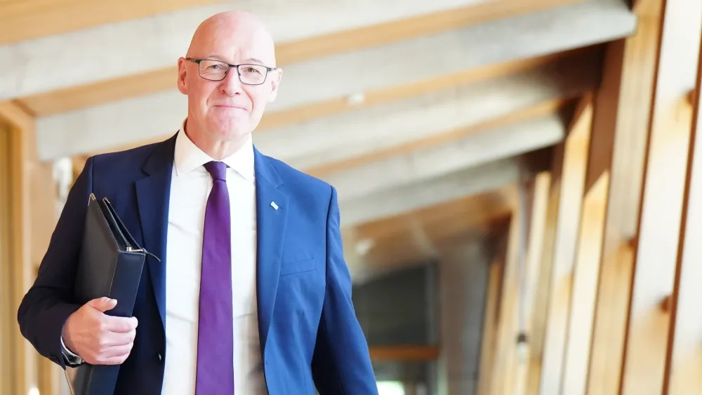 John Swinney carrying a folder in a Holyrood corridor