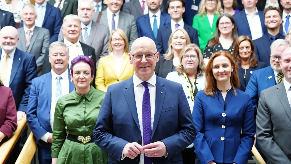John Swinney standing in front of the SNP group