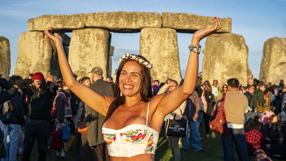 A woman welcomes the sun at Stonehenge, Wiltshire