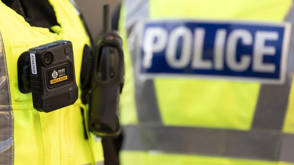 A police officer in uniform, with a body-worn camera on their hi-vis vest