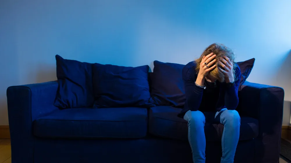 Woman sitting on sofa with head in hands